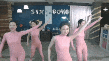 a group of women in pink jumpsuits are dancing in front of balloons that say six boys