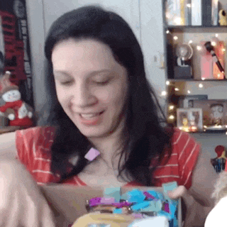 a woman in a red and white striped shirt is opening a gift box .