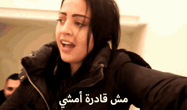 a woman wearing a black jacket with arabic writing on the bottom
