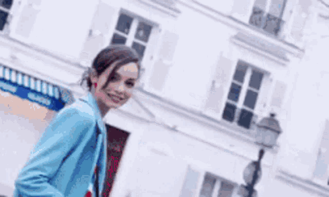 a woman in a blue jacket is walking down the street