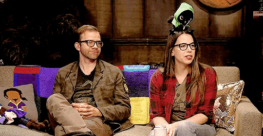 a man and a woman are sitting on a couch with a stuffed animal on the woman 's head