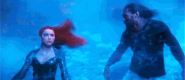 a man and a woman are standing in the water .
