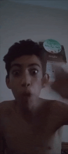 a shirtless young boy is making a funny face in front of a calendar .