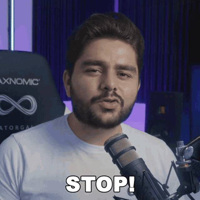 a man with a beard stands in front of a microphone saying stop