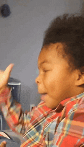 a young boy wearing a plaid shirt is making a face