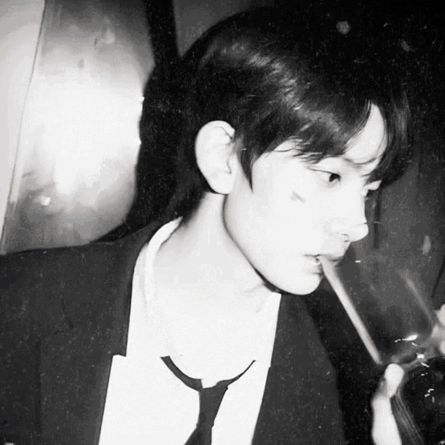 a man in a suit and tie is drinking from a glass with a straw