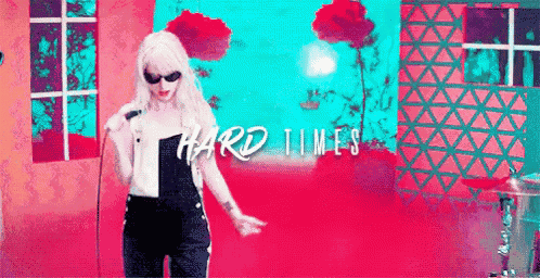 a woman is singing into a microphone in front of a pink wall .
