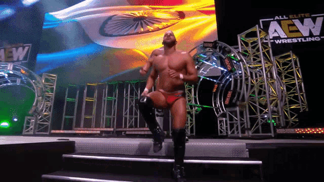 a wrestler stands on stage in front of a sign that says aew