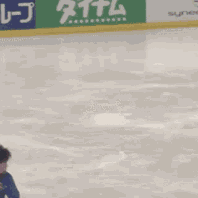 a person is skating on an ice rink with a green sign that says synergice
