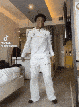 a man in a white adidas shirt and white pants is dancing in a room