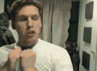 a man in a white shirt is adjusting his tie in front of a mirror in a room .