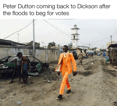 a man in an orange suit walks down a dirt road