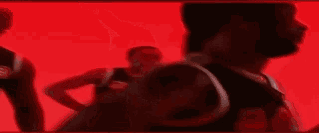 a woman is dancing in front of a red background in a dark room .