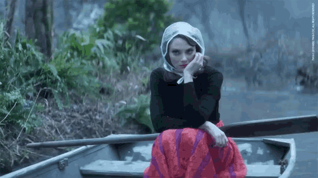 a woman in a red skirt sits in a boat with a watermark that says tmc on it