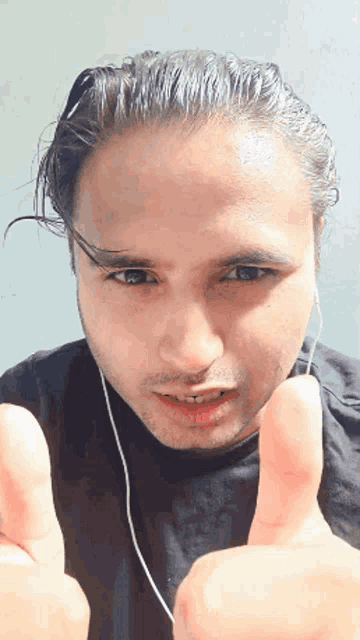 a man wearing earbuds is giving a thumbs up sign
