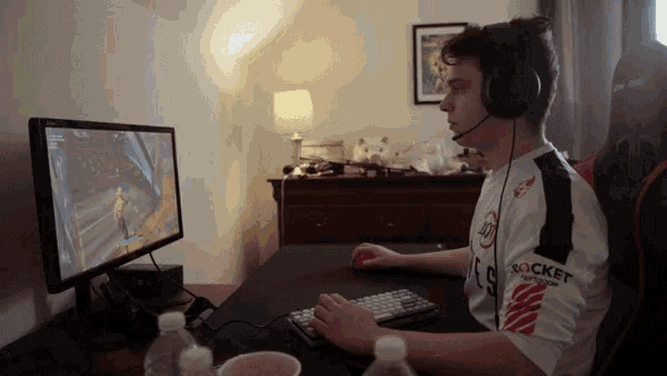a man wearing a rocket league shirt is playing a video game on a computer