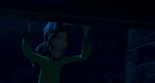 a cartoon character in a green shirt is hanging from a beam in the dark