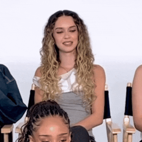 a woman with curly hair is sitting in a director 's chair .