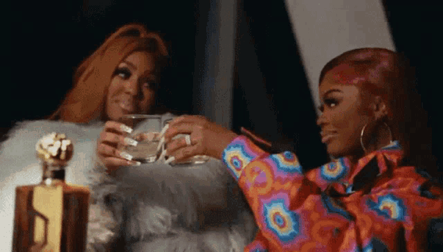 two women are sitting next to each other holding glasses of water .