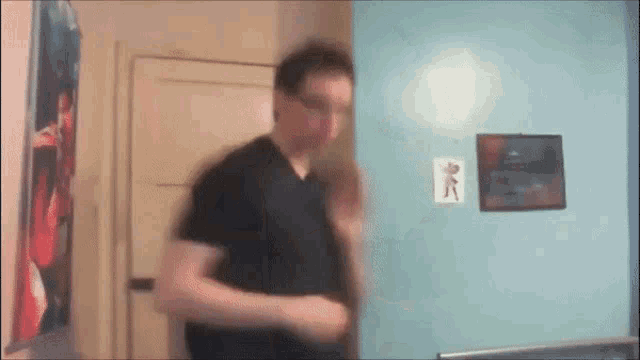 a man in a black shirt is standing in front of a blue wall with a picture of a man on it
