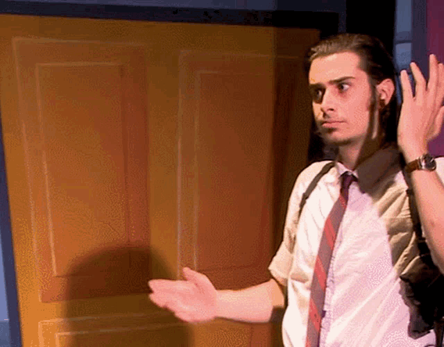 a man in a white shirt and tie is standing in front of a yellow door