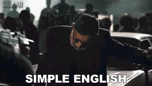 a man with glasses and a hat is standing next to a car with the words simple english written below him