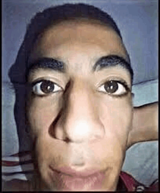 a close up of a young man 's face with a big nose making a funny face .