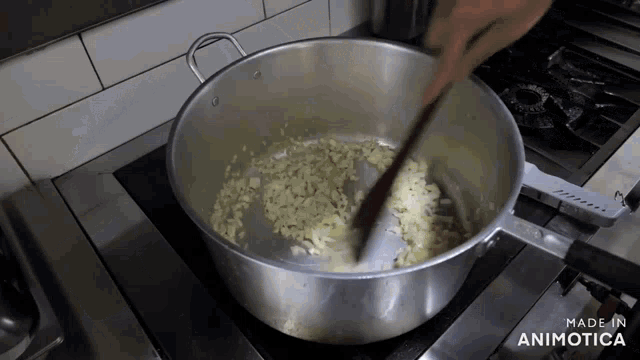 a pot of food is being stirred with a wooden spoon and the words made in animotica are visible on the stove