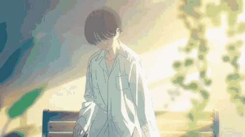 a boy in a white shirt is standing in front of a tree