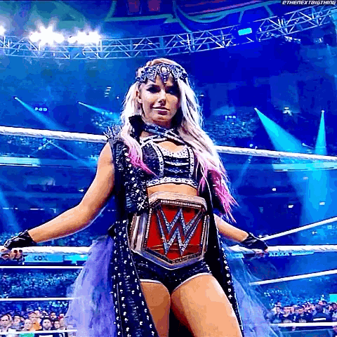 a woman is standing in a wrestling ring with a wwe championship belt on her waist .