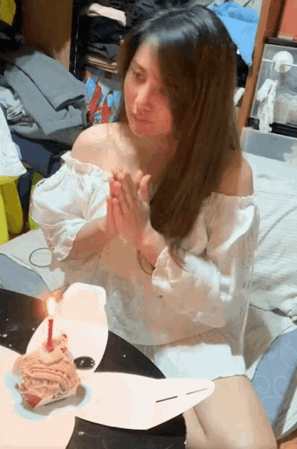 a woman sits at a table with a cake and a candle on it