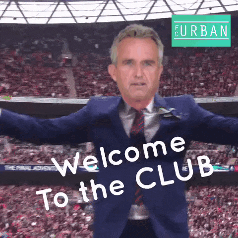 a man in a suit says welcome to the club in front of a crowd