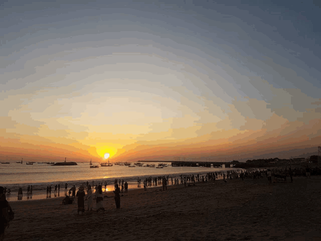 a group of people gathered on the beach at sunset