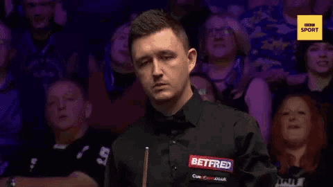 a man in a betfred shirt stands in front of a crowd of people