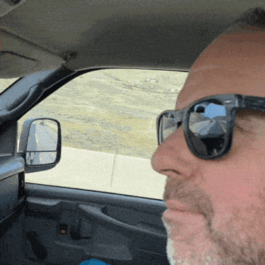 a man wearing sunglasses is sitting in a car