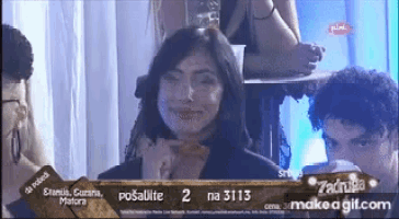 a woman is smiling while sitting in front of a group of people on a tv screen .