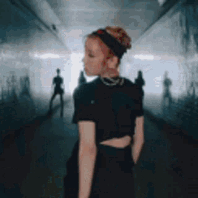 a woman in a black dress is standing in a tunnel with people standing in the background .