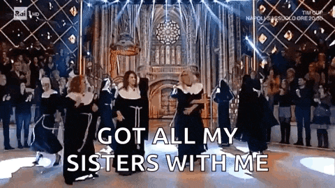 a group of nuns are dancing on a stage while a crowd watches .