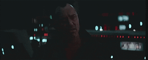 a man with a beard is looking at something in the dark