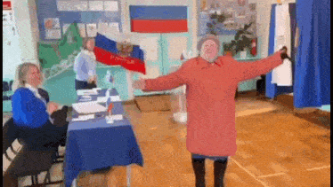 a woman in a red coat is dancing in a room with a russian flag .