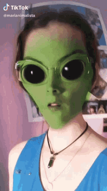 a girl wearing a green alien mask and sunglasses