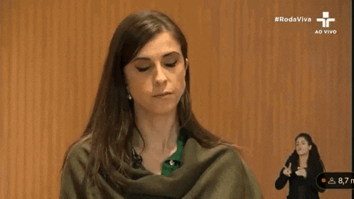 a woman wearing a green scarf is sitting in front of a sign language sign .