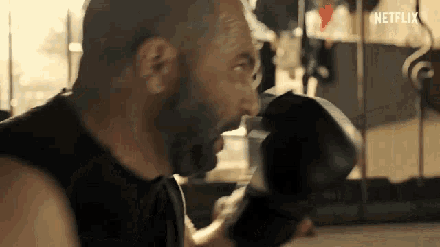 a man is wearing boxing gloves and making a funny face in a gym .