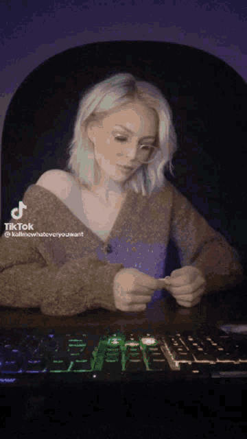 a woman is sitting at a desk with a keyboard and a tik tok sticker
