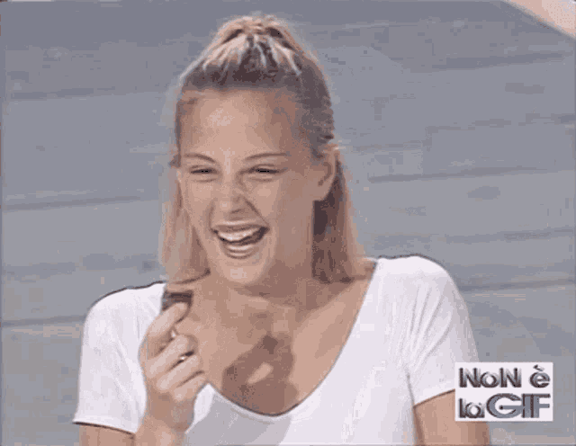 a woman in a white shirt is laughing and holding a piece of chocolate