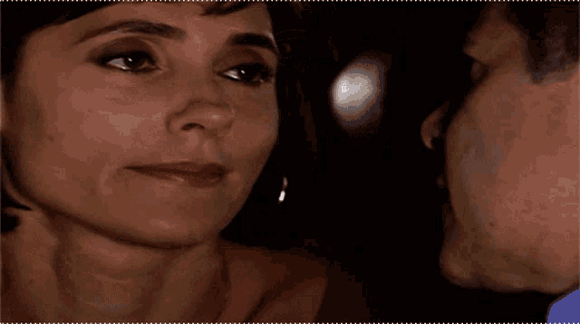 a close up of a woman 's face with a man 's face in the background