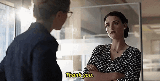 two women are standing next to each other in an office talking to each other and one of them is saying `` thank you '' .
