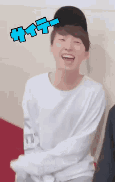 a young man wearing a white shirt and a black hat laughs