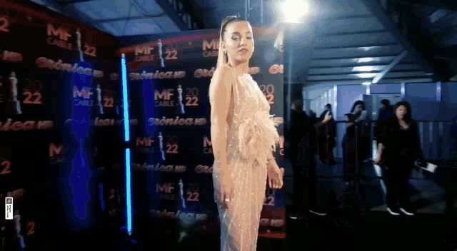 a woman in a dress stands in front of a wall that says mf cable 22