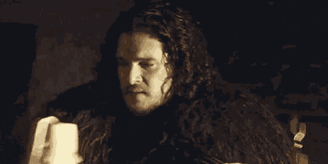 a man with long hair and a beard looks down at something